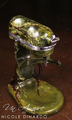 an old fashioned green mixer sitting on top of a table next to a brown floor