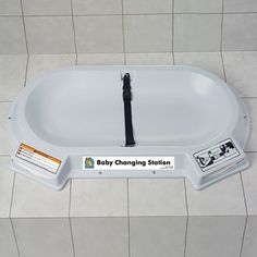 the baby changing station is located on the tiled floor and has two tags attached to it