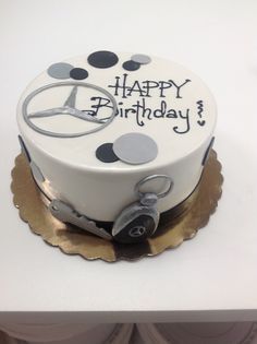 a white birthday cake with black and silver decorations