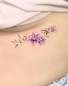 a woman's lower back tattoo with flowers on her left side ribcage