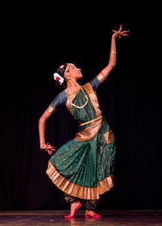 a woman in a green and gold sari dancing