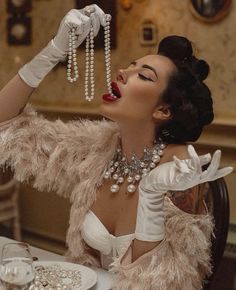 a woman in white gloves and dress with pearls on her head