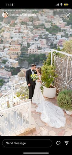 a bride and groom kissing on top of a balcony with the city in the background