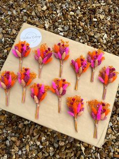 flowers are arranged on a piece of paper and placed on the ground with gravel around them