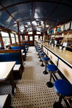 the inside of a restaurant with blue stools and tables on either side of the bar