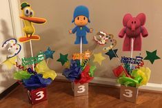 three cupcake toppers in the shape of cartoon characters on sticks with numbers and stars