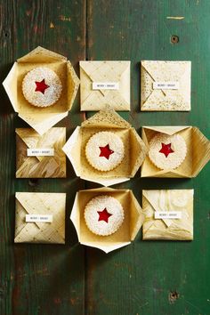 several boxes with pastries in them sitting on a green tableclothed surface, one has a red star and the other is empty