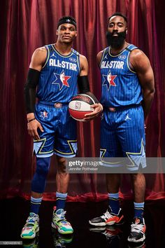 two basketball players standing next to each other in front of a red curtain holding a ball