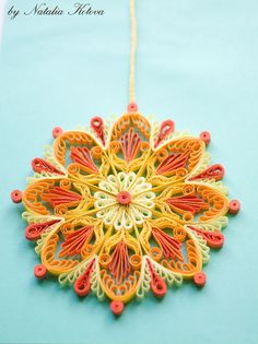 an ornament made out of colored paper on a blue tablecloth with string