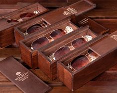 three wooden boxes with sunglasses in them on a table