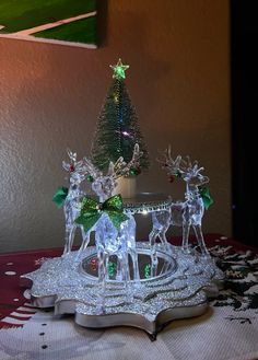 a lighted christmas tree on top of a table with reindeer figurines around it