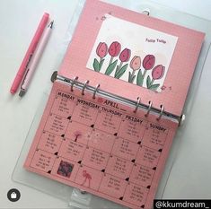 a pink planner with flowers on it next to a pen