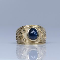 This captivating ring features a 2.05-carat blue sapphire cabochon, set in a sleek satin-finish 14k yellow gold band. The deep blue hue of the sapphire is beautifully enhanced by the soft, matte texture of the gold, creating a sophisticated and modern aesthetic. Perfect for those who appreciate understated elegance, this ring is a timeless piece that adds a touch of luxury to any collection. Size: 6.25 Metal Type: 14K Yellow Gold Weight: 5.8G Width: 13.25mm to 3.80mm at shank Finger to Top of Ring: 7.06mm Hallmarks:14k N Center Stone Details:  Type: Sapphire Cut: Oval Cabochon Carat: Aprox 2.05ct Color: Deep Blue We look forward to providing you with an exceptional experience and helping you find more exquisite additions to your collection. *More Pictures Available on Request* Oval Cabochon Sapphire Ring With Bezel Setting For Anniversary, Anniversary Sapphire Ring With Bezel Setting, Oval Cabochon Bezel Set Sapphire Ring For Anniversary, Anniversary Oval Cabochon Sapphire Ring With Bezel Setting, Yellow Gold Domed Sapphire Ring, Formal Blue Oval Cabochon Moonstone Ring, Gold Sapphire Ring With Oval Cabochon Bezel Setting, Oval Cabochon Sapphire Ring With Bezel Setting, Classic Yellow Gold Sapphire Ring With Cabochon