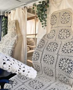 a crocheted chair sits in front of a window with curtains on the outside