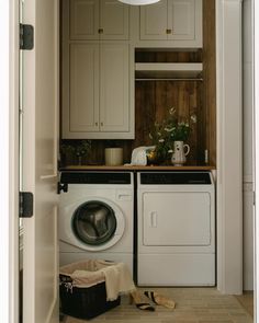 a washer and dryer in a small room with wooden cabinets on the wall