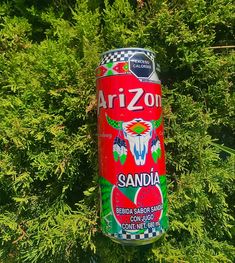 a can of arizona soda hanging from a tree in front of some green leaves and bushes