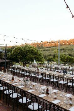 tables and chairs are set up for an outdoor event with string lights strung over them