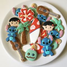 a white plate topped with cookies covered in cartoon character icing next to a guitar