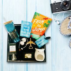 the contents of a travel bag laid out on a blue wooden table next to an old camera