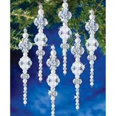 four crystal ornaments hanging from a christmas tree in front of a blue background with snowflakes