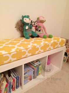 a stuffed animal sits on top of a book shelf next to other books and toys