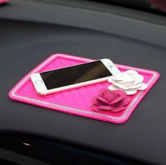 a cell phone sitting on top of a pink car seat belt with flowers attached to it