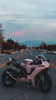 a pink motorcycle is parked on the street