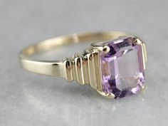 Outstanding! This modern yellow gold setting perfectly frames the amethyst we've set at the center! The tapering stepped yellow gold band looks soft and elegant on the finger, while the rich purple gem glitters with violet sparkles! Metal: 14K Yellow Gold Gem: Amethyst 2.85 Carats Gem Measurements: 7.8 x 9.9 mm, Emerald Cut Ring Size: 10 Marks: "14K UP" Stamped on the inside band Art Deco Amethyst Ring In Yellow Gold, Yellow Gold Amethyst Ring In Art Deco Style, Art Deco Yellow Gold Amethyst Ring, Modern Yellow Gold Amethyst Ring For Wedding, Modern Yellow Gold Amethyst Wedding Ring, Gold Solitaire Amethyst Ring For Formal Occasions, Gold Amethyst Ring With Modern Style, 10 Marks, Purple Gems