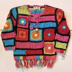 a colorful crocheted sweater with fringes and buttons