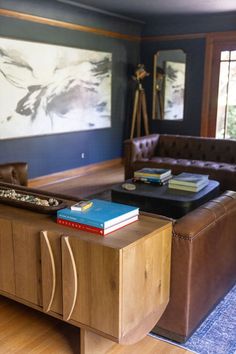 a living room filled with furniture and a large painting on the wall above it's coffee table