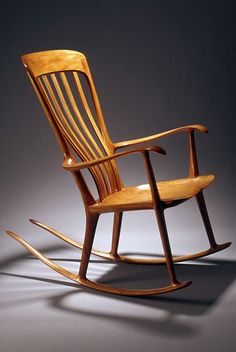 a wooden rocking chair sitting on top of a gray floor