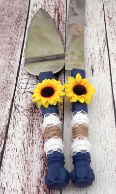 two sunflowers sitting on top of blue and white striped utensils next to each other