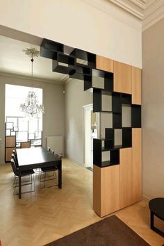 a dining room table and chairs in front of a wall with black squares on it