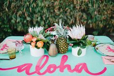 an aloha table with pineapples and succulents on it