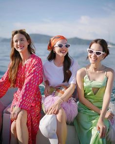 three women sitting on the back of a boat