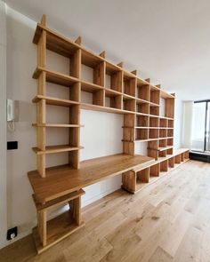 an empty room with wooden shelves on the wall and hard wood flooring in front of it