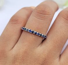 This Ring comes with a 100% Natural Blue Sapphire Gemstone and it is made up of 925 solid sterling silver. This ring is handcrafted by our skilled craftsmen and designed by us. Every gemstone is handpicked for the best quality.  Materials:- Silver (925 Solid Sterling Silver) Item Weight :- Approx. 2.00 Grams Gemstone:- Natural Blue Sapphire Stone Size :- 2mm  Stone Shape :- Round Cut Select Size in Variation, if you don't find perfect size please buy any size and message us your size we'll make. White Gold Sapphire Stackable Jewelry, Sapphire Stackable Rings With Prong Setting For Anniversary, Stackable White Gold Sapphire Jewelry, Sapphire Eternity Band With Vvs Clarity, Anniversary Sapphire Stackable Rings, Round Sapphire Eternity Band With Vvs Clarity, White Gold Sapphire Eternity Band, Sterling Silver Jewelry Half Eternity Round Shape, Sterling Silver Half Eternity Round Jewelry