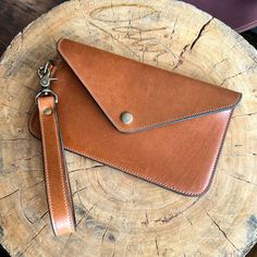 a brown leather wallet sitting on top of a tree stump next to a pair of scissors