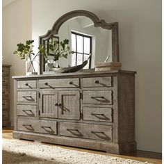 an old dresser with a mirror and potted plant