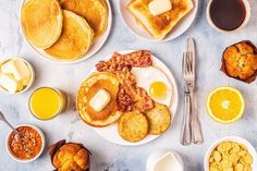 breakfast foods laid out on plates with coffee, orange juice and croissants