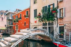 a small bridge over a body of water in front of buildings with flowers on them