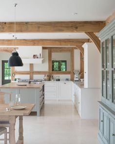 a large kitchen with wooden beams and white cabinets