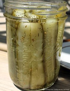 a jar filled with pickles sitting on top of a wooden table