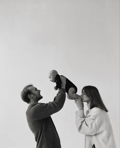 a man holding a baby up to his face as he holds it in the air