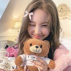 a girl holding a brown teddy bear in her hands