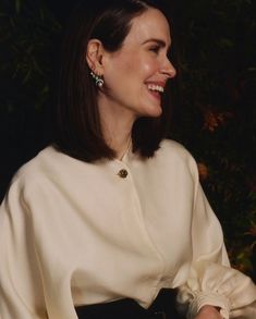 a woman sitting in front of a bush smiling