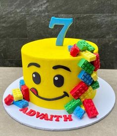 a birthday cake made to look like a smiley face with legos around it and the number seven on top