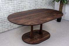 a wooden table sitting in front of a brick wall next to a potted plant