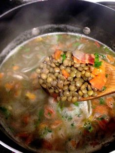 peas and carrots are being cooked in a pot with a wooden spoon on the stove