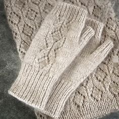 two white knitted gloves sitting on top of a gray carpet next to each other